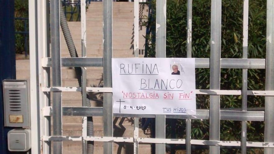 Cartel con la imagen de una fallecida, en la puerta de la residencia Los Pinos.