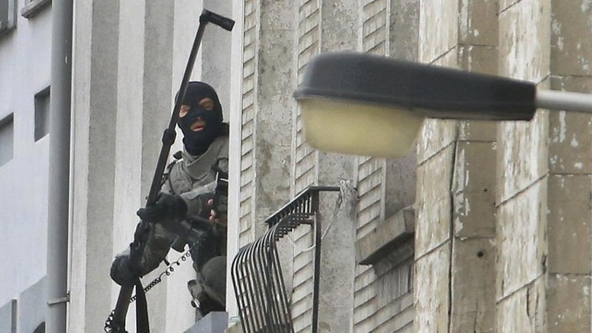 Un agente utiliza una cámera extendida para espiar en el interior de un piso, en Molenbeek, este lunes.