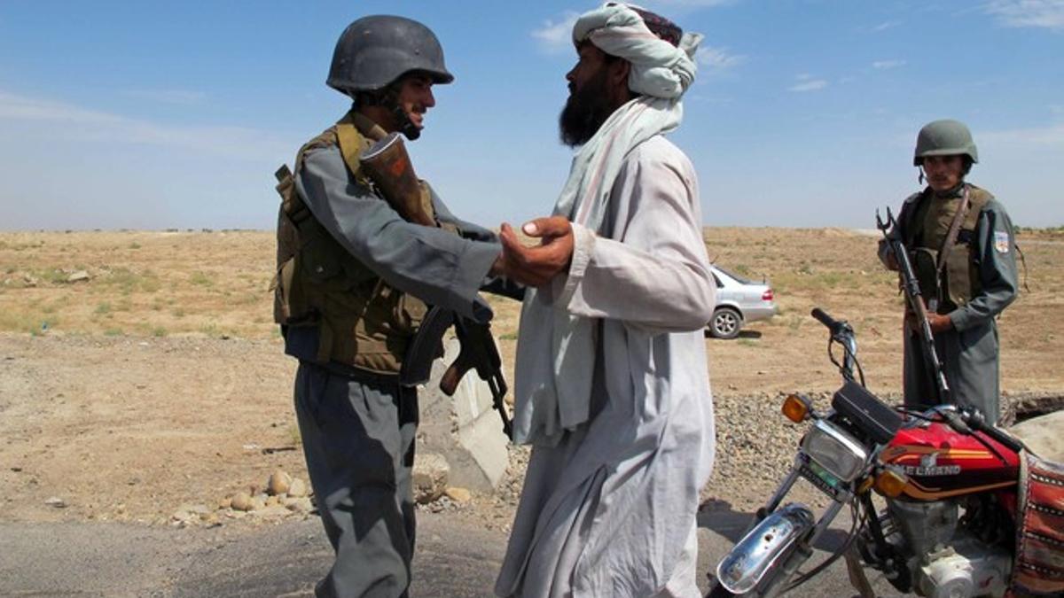 Un policía afgano cachea a un ciudadano en un punto de control en la ciudad de Lashkar Gah tras la fin del proceso de paz.