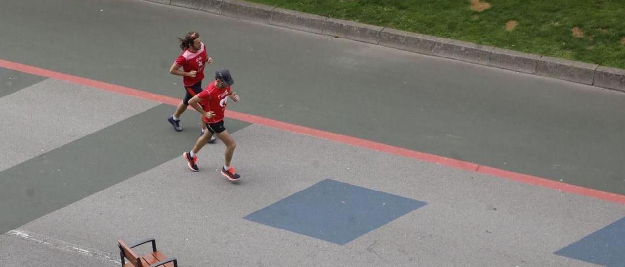 Dos jóvenes corren por el “cascayu”, con la franja verde que será peatonal al fondo. | Ángel González
