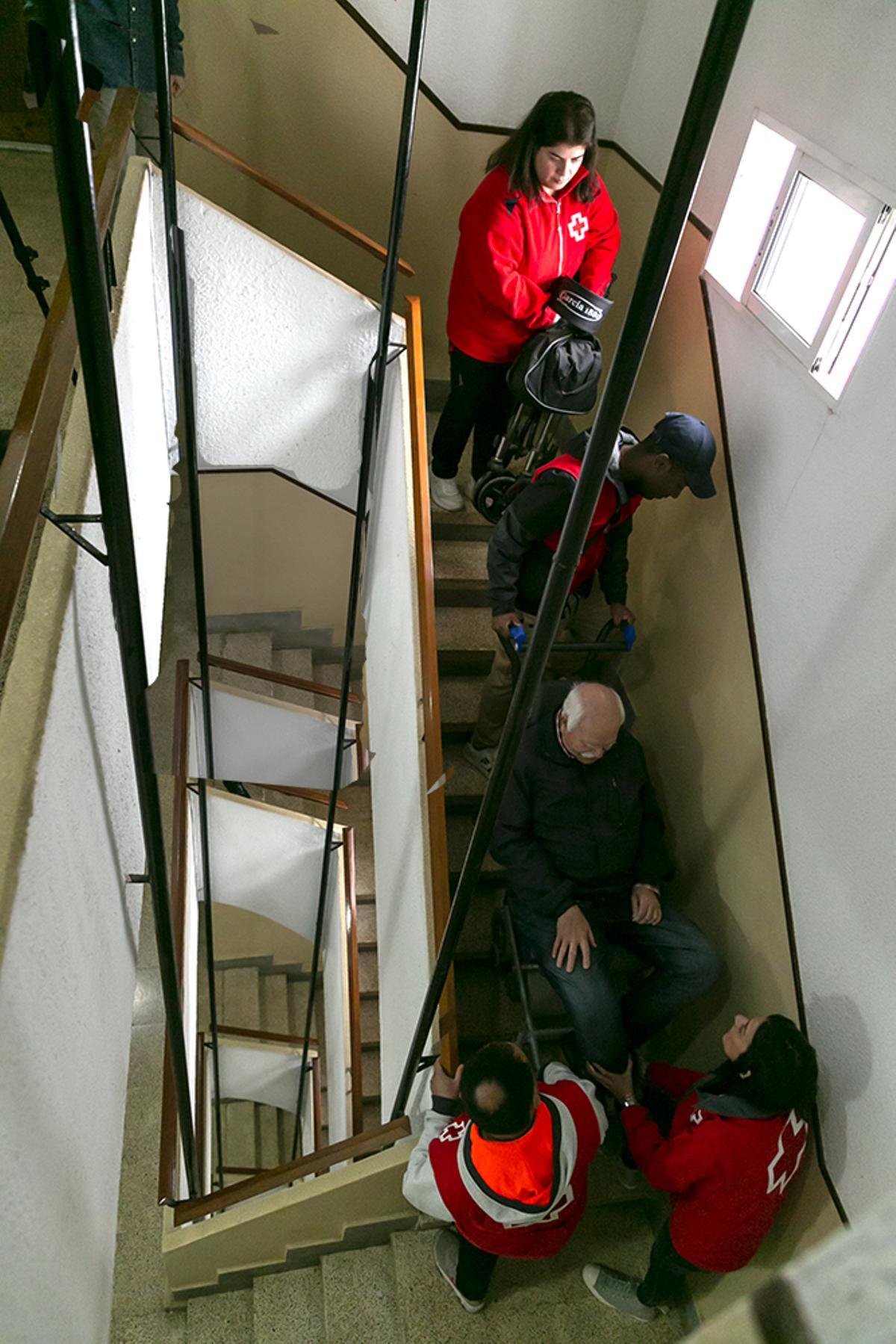 Un equipo de Cruz Roja baja al vecino desde el cuarto piso con una silla especial.