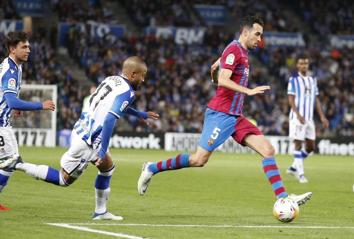 SAN SEBASTIÁN, 21/04/2022.- El centrocampista del FC Barcelona Sergio Busquets (d) juega un balón ante Rafinha Alcántara (c), de la Real Sociedad, durante el partido de Liga en Primera División que disputan hoy jueves en el Reale Arena, en San Sebastián. EFE/Juan Herrero