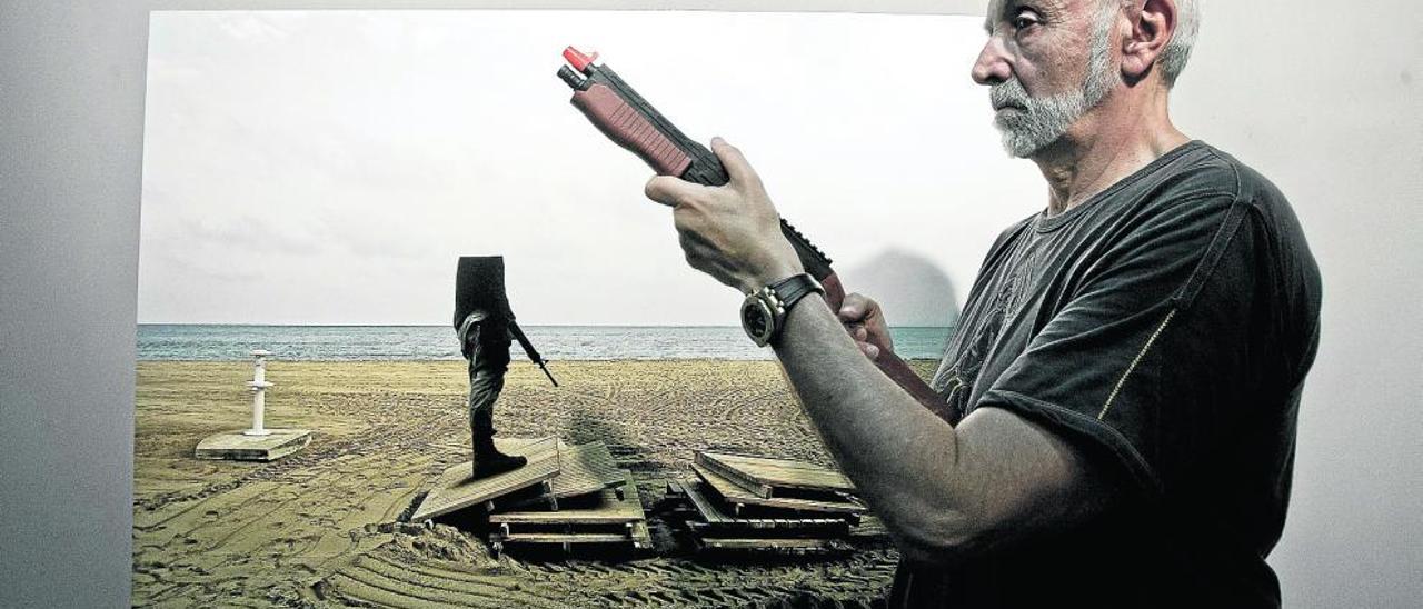 Pepe Calvo, con un arma de juguete, delante de una de las fotografías de su exposición en L´Espai.