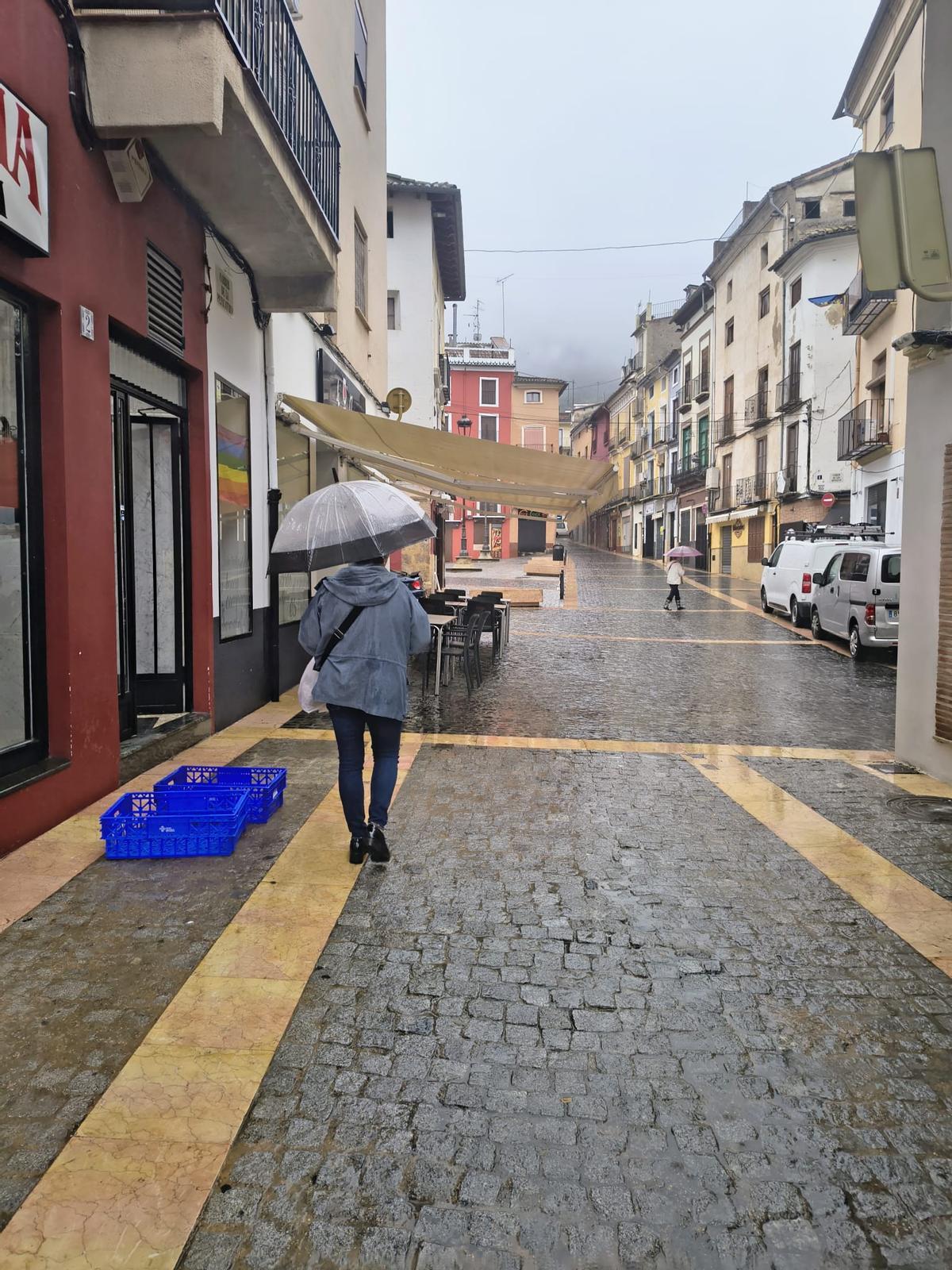 Dos mujeres pasean con sus paragüas por las inmediaciones de la Plaça del Mercat de Xàtiva, hoy.