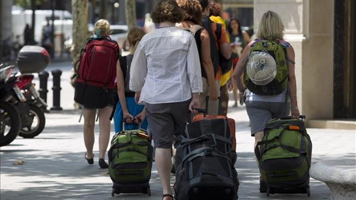 Un grupo de turistas cargan maletas por el paseo de Gràcia en busca de su hotel.