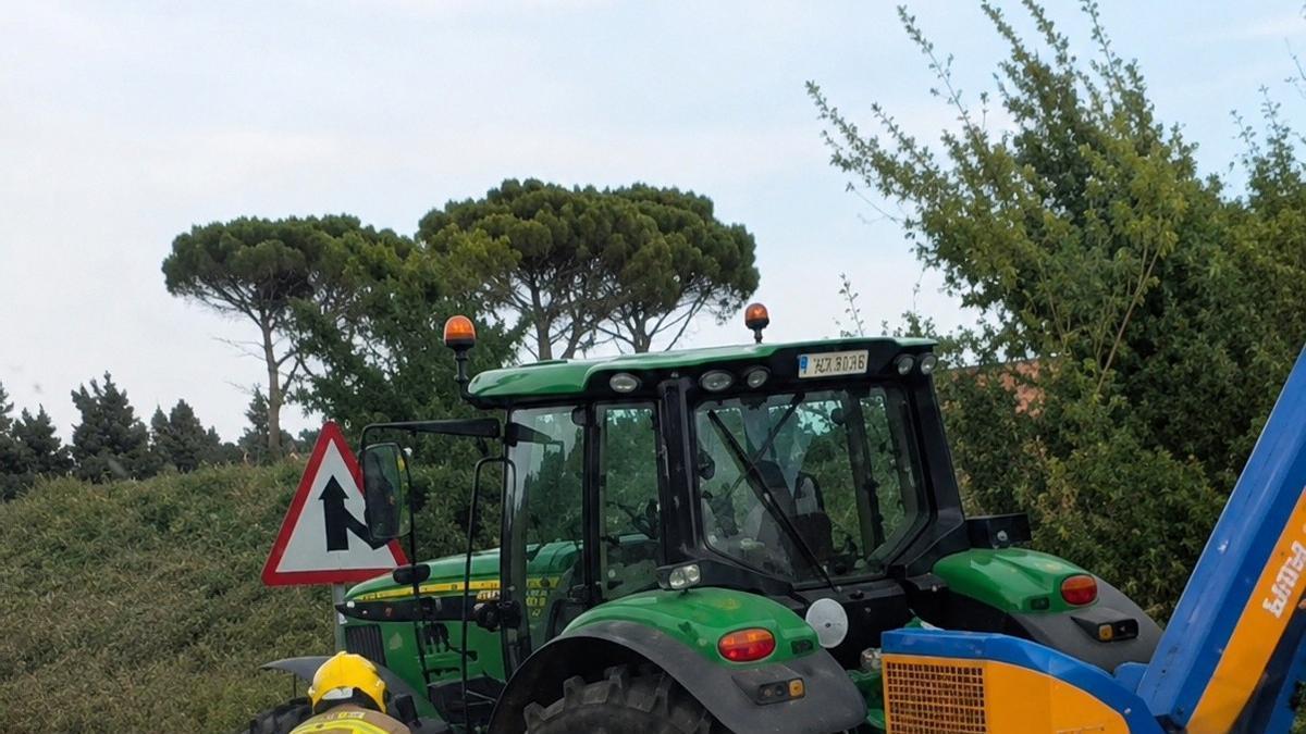 Un bomber i el tractor amb els danys patits arran del xoc a Caldes de Malavella.