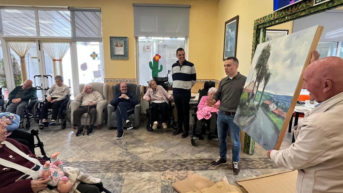 Iván Fernández y José Luis Montes muestran el cuadro entregado al geriátrico de Molleda.