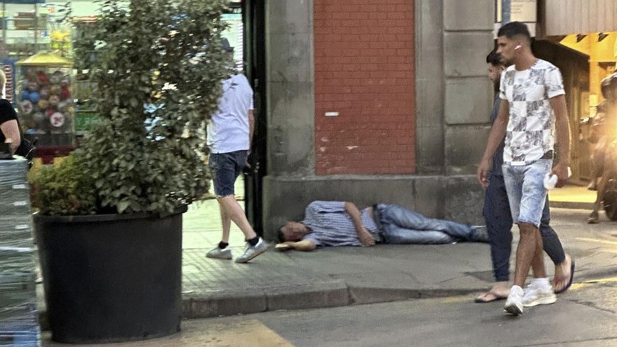 Una persona beguda estirada al costat de la botiga que genera els problemes que denuncien els veïns