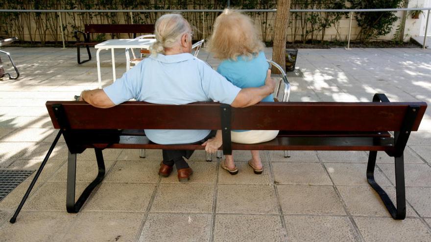 Una pareja de ancianos, sentados en un banco.