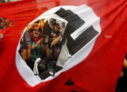 Demonstrators burn a flag emblazoned with a swastika during a demonstration against the visit of German Chancellor Angela Merkel in central Athens