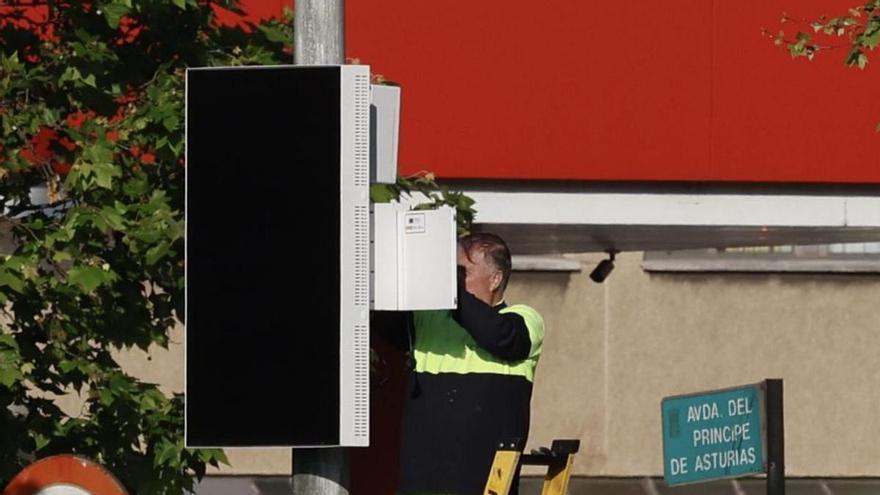 Un técnico instala un panel informativo en el ámbito de la zona de bajas emisiones de La Calzada. | MARCOS LEÓN
