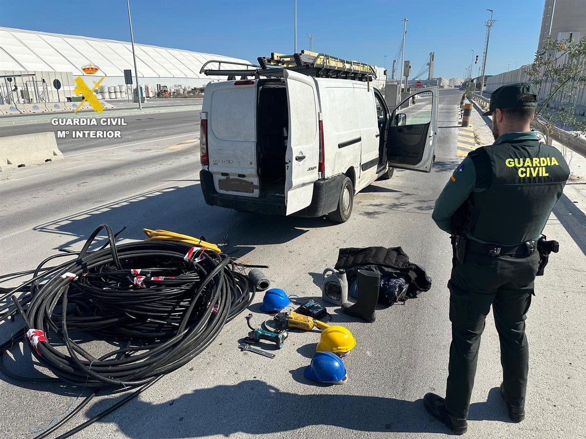 Un agente junto a parte de la mercancía intervenida y la furgoneta que la transportaba.