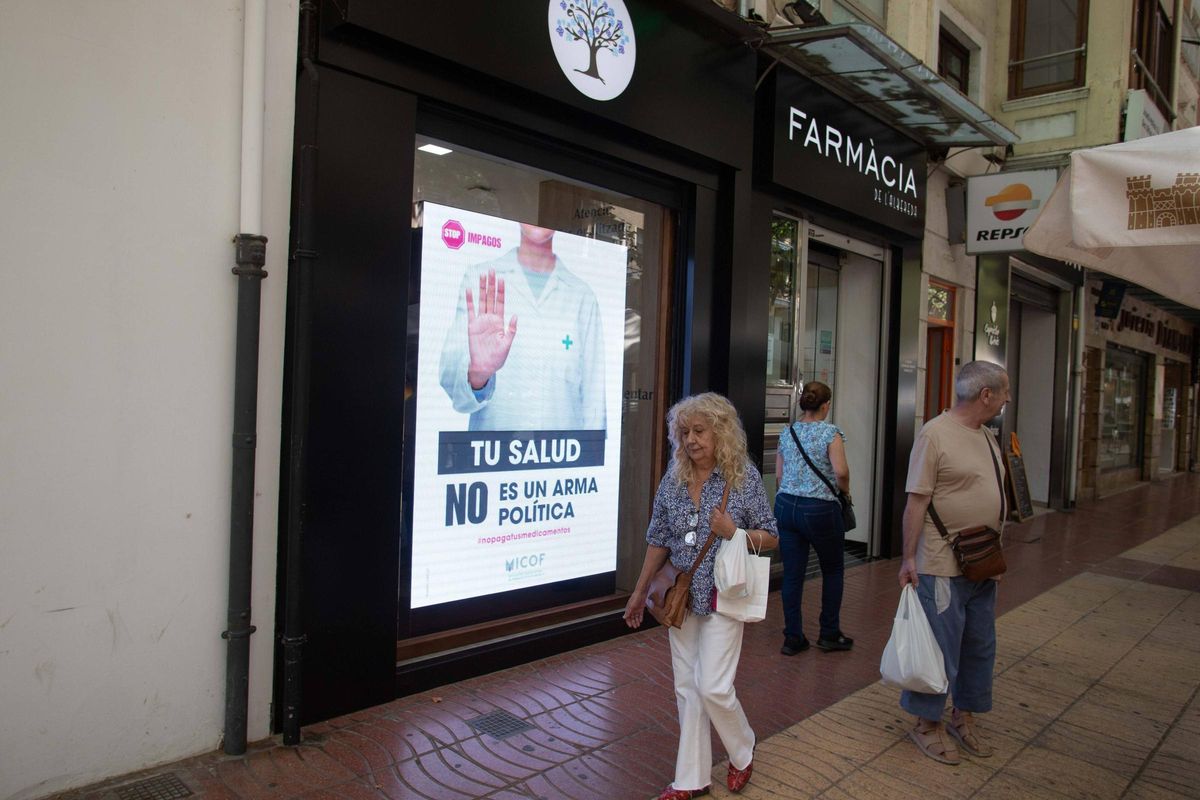Varios viandantes pasan por delante de la facha de la farmacia de l'Albereda de Xàtiva, ayer.