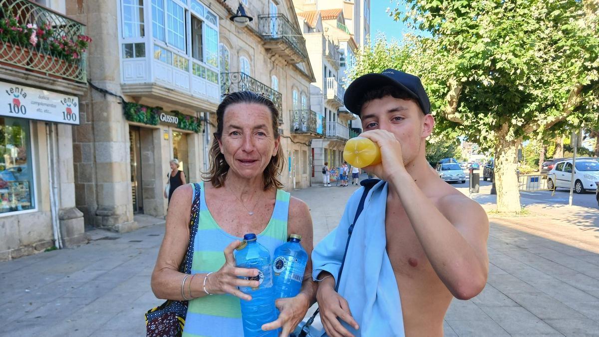Dos personas hidratándose mientras pasean por las calles del centro de Cangas.