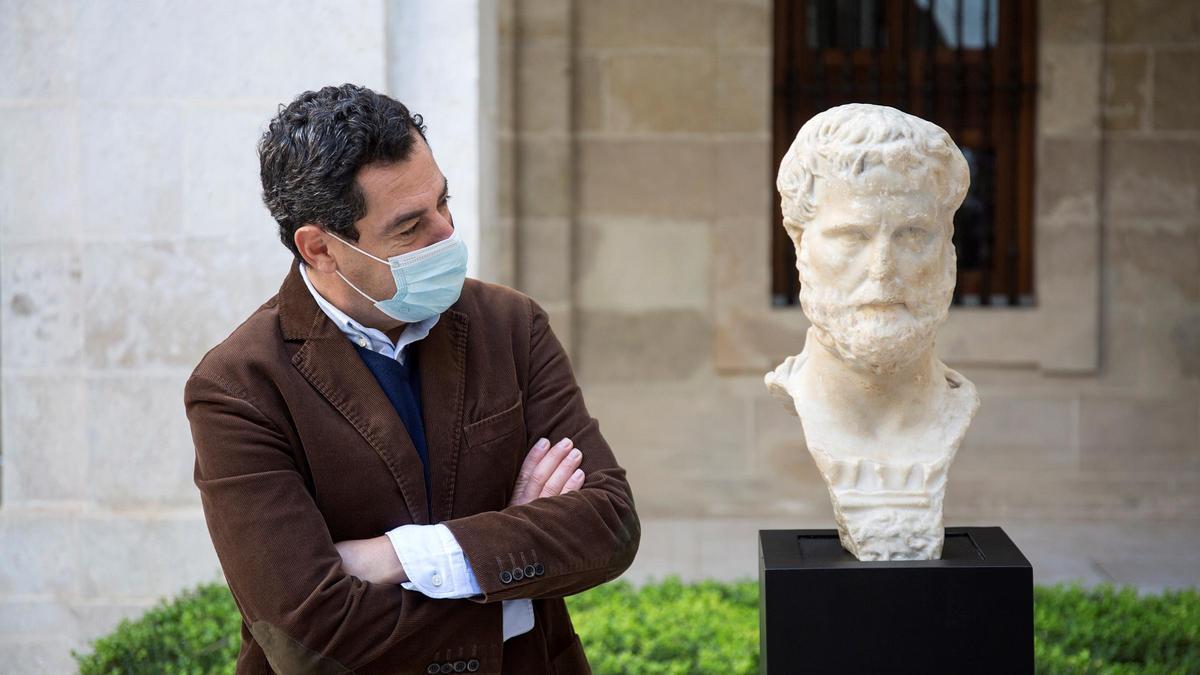 El presidente de la Junta de Andalucía, Juanma Moreno, junto al busto romano.