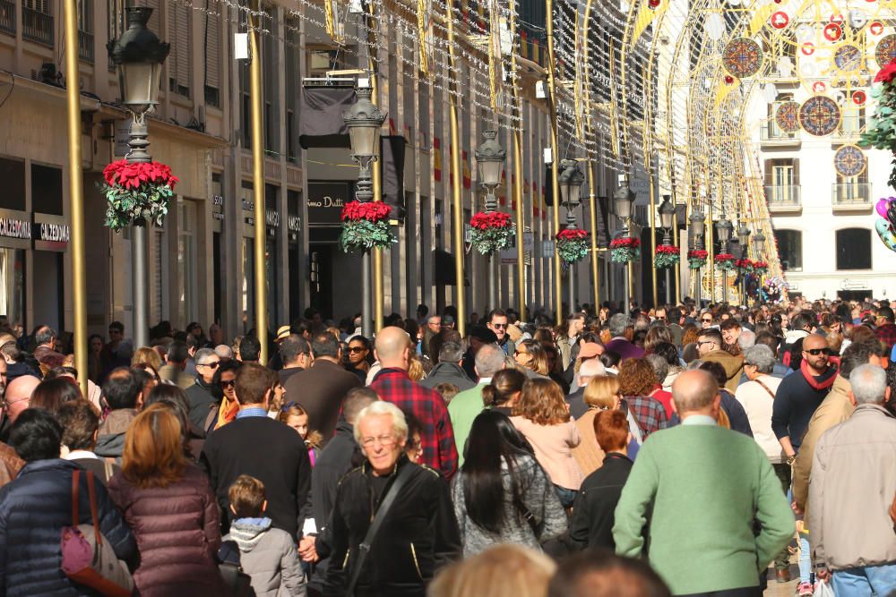 Muchos malagueños y turistas aprovechan el buen tiempo y el día festivo por la Inmaculada Concepción para pasear y realizar las compras navideñas en el Centro de Málaga.