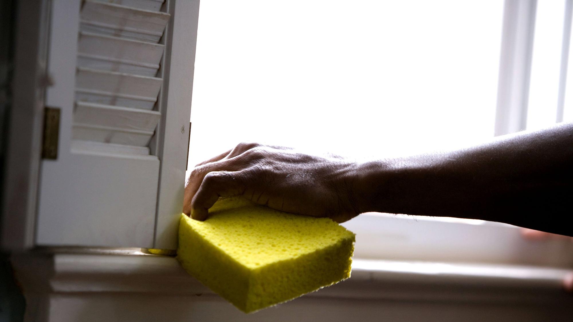 Una persona limpia el riel o hueco de la ventana