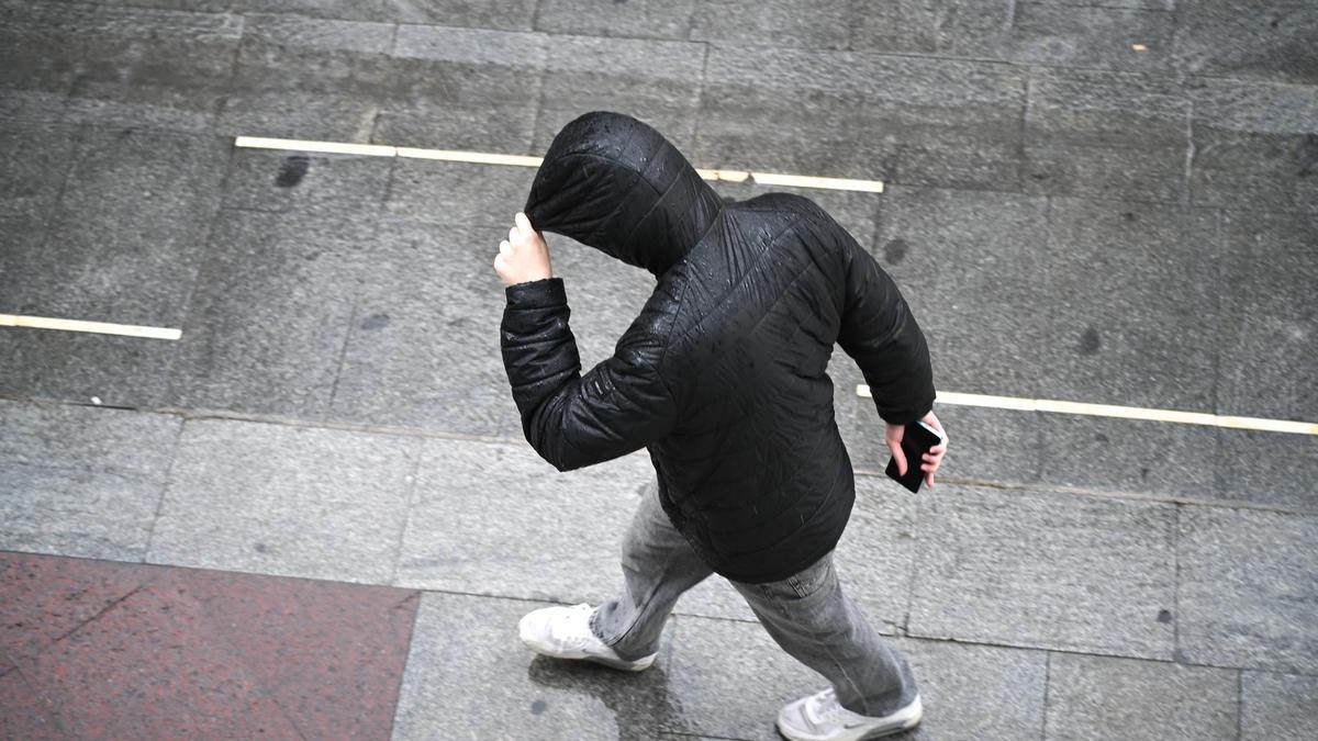 Un joven se refugia de la lluvia en Elche