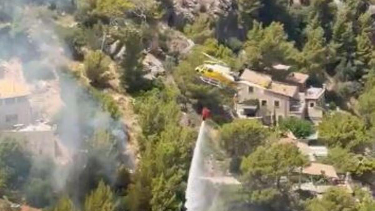 Un helicóptero del Ibanat descarta agua este domingo sobre un pinar incendiado en Deià.