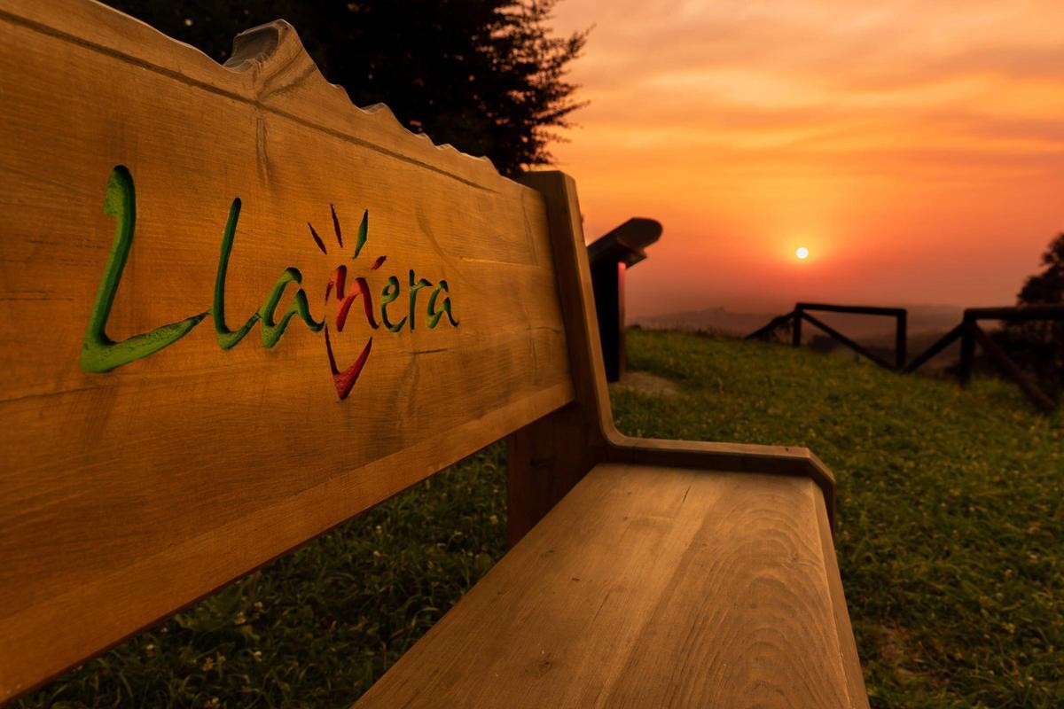Atardecer en Santu Firme, donde hay uno de los bancos con el nombre del municipio, en cuyo centro se ve el símbolo de uno de sus lemas, "El corazón de Asturias"