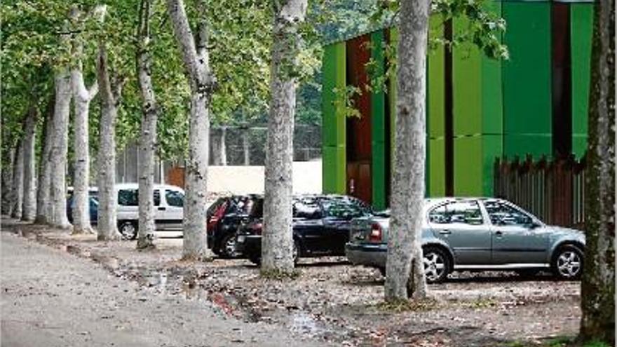 Cotxes estacionats als aparcaments de terra al costat de la Piscina Municipal de la Devesa.