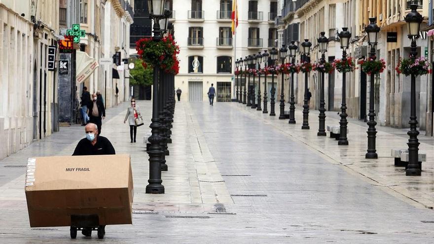 Una persona transporta un pedido por la calle Larios.