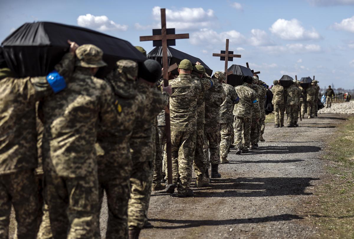 Funeral militar ucraniano en el cementerio de Dnipro. Un grupo de soldados cargan los ataúdes de sus compañeros muertos.