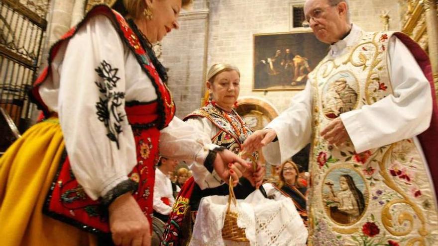 Varias mujeres, ataviadas con trajes tradicionales, realizan su ofrenda.