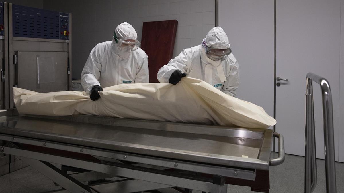 Al llegar al hospital de Mataró, los funerarios recogen el cuerpo de la morgue, que ya viene envuelto en una bolsa de plástico. De allí lo colocan directamente en el ataúd, que queda sellado para evitar contagios.