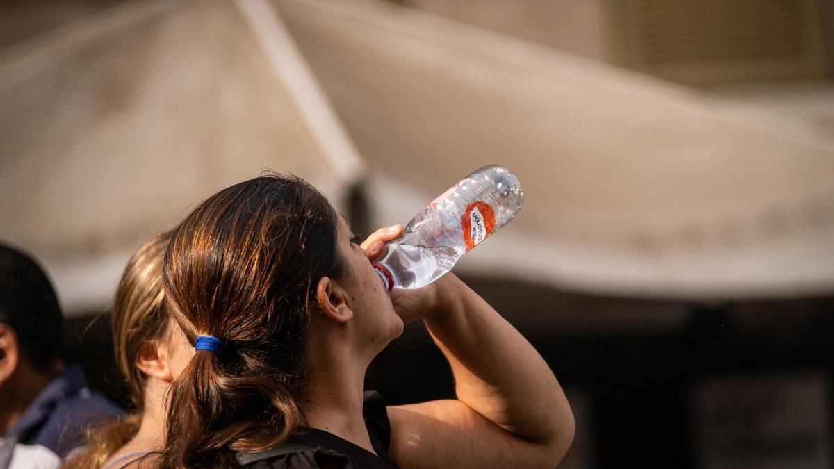 Una mujer toma agua para refrescarse y mitigar el calor.