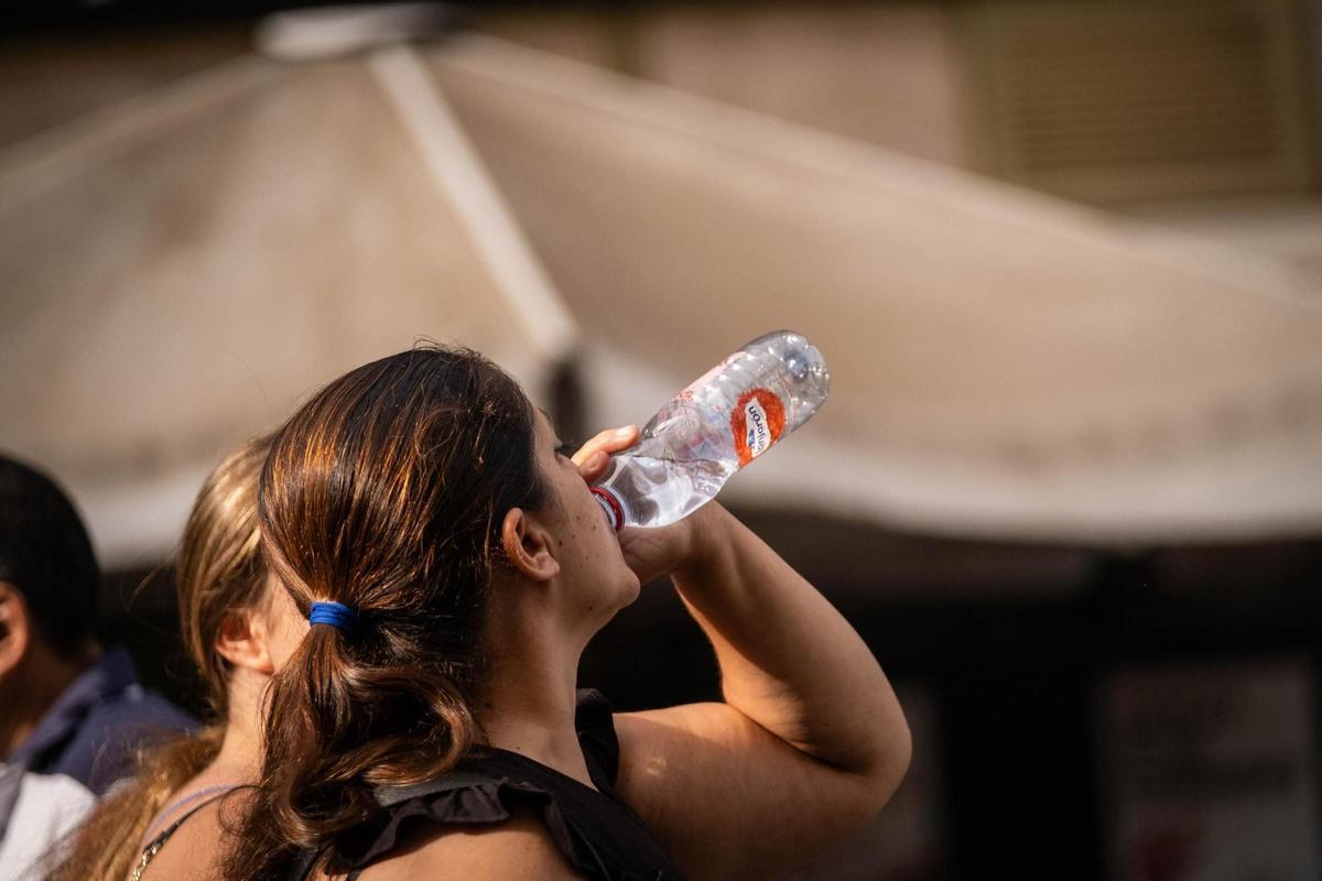 Una mujer toma agua para refrescarse y mitigar el calor.