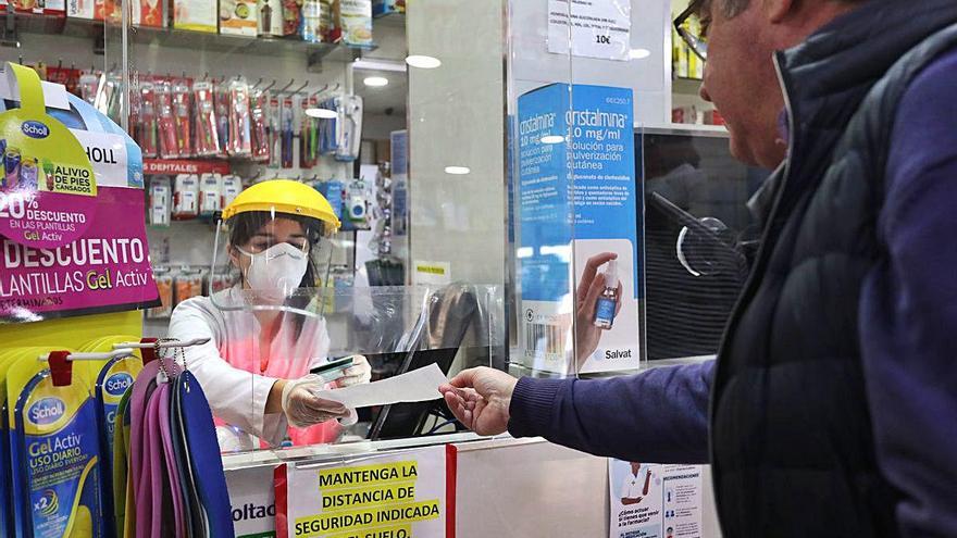 Una farmacéutica reparte las mascarillas donadas por la Generalitat para la población de riesgo.