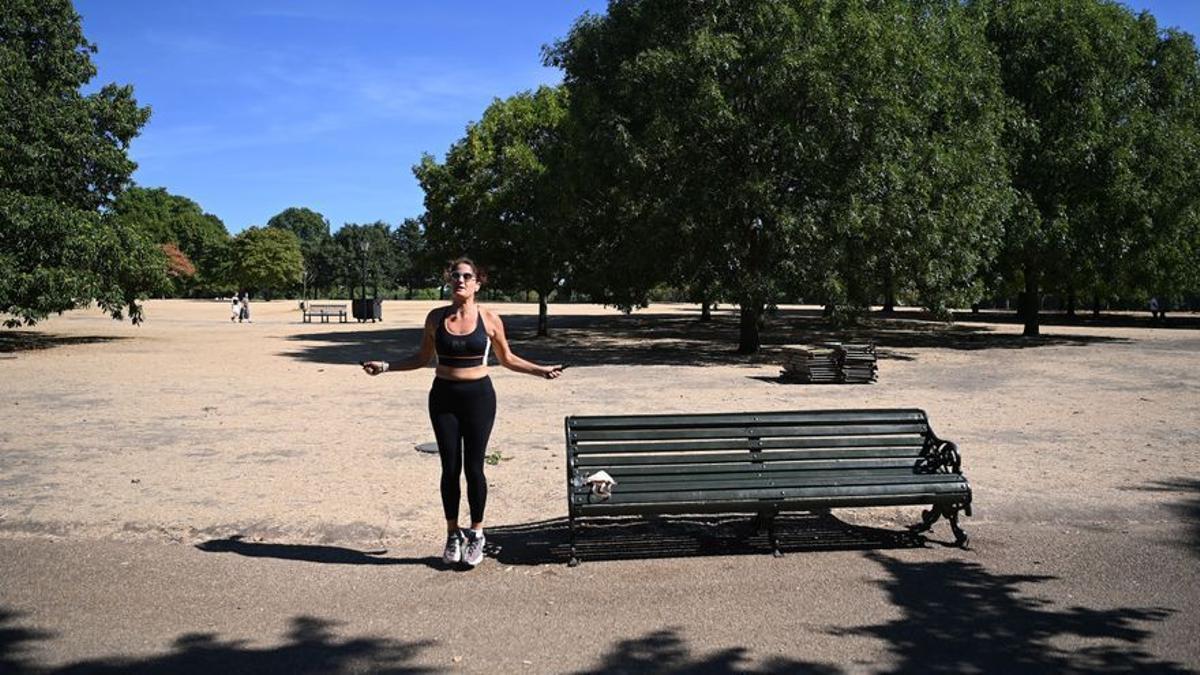 Una mujer hace ejercicio en un reseco Hyde Park en Londres.