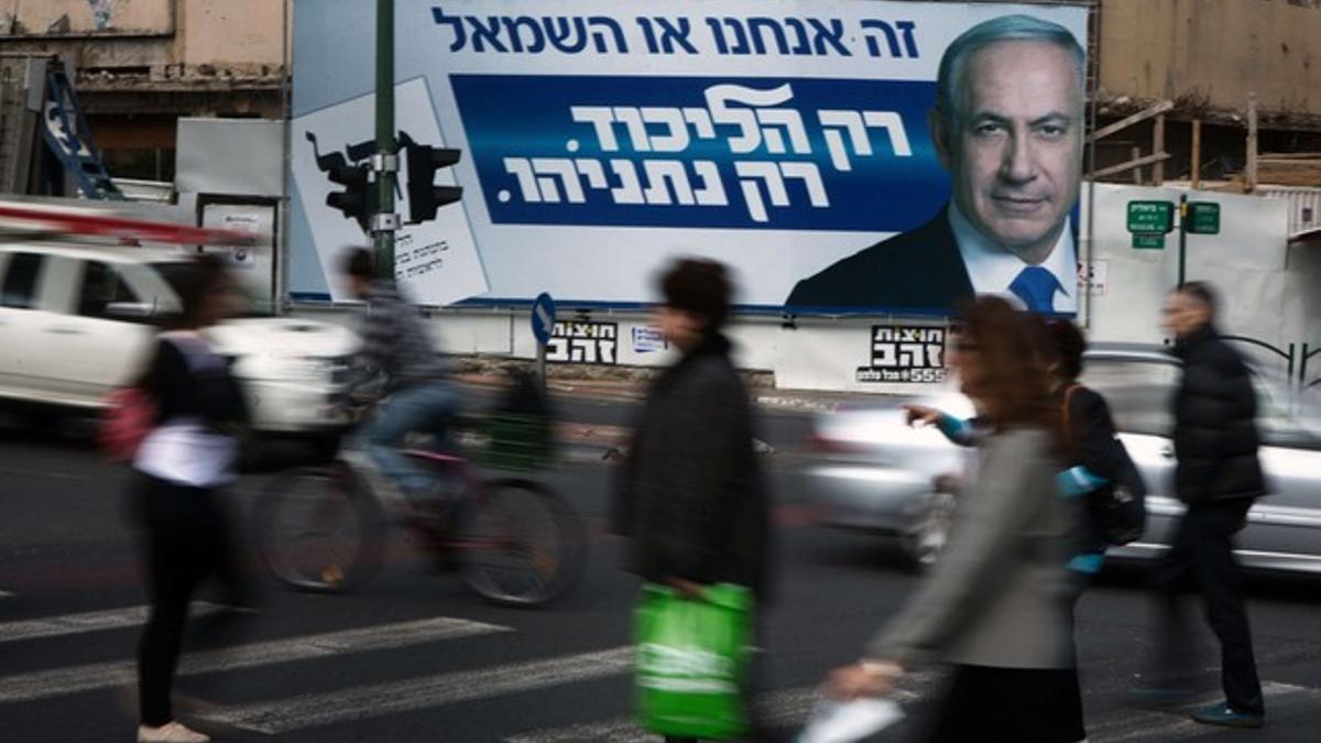 Un cartel propagandístico de Binyamin Netanyahu observa pasar a los ciudadanos israelís.
