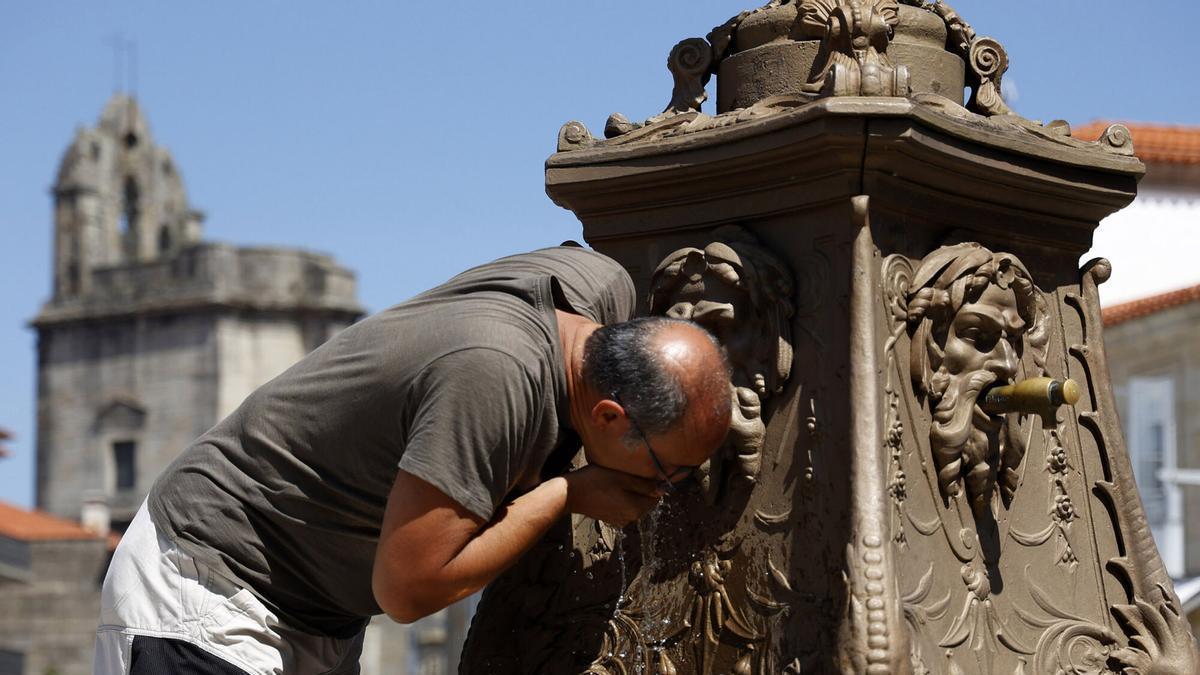 Un hombre se refresca en una fuente en Pontevedra.
