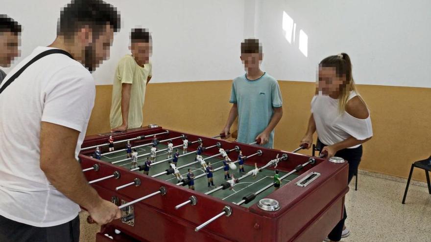 Varios jÃ³venes juegan con la educadora al futbolÃ­n, antes de retirarlo de esta sala.