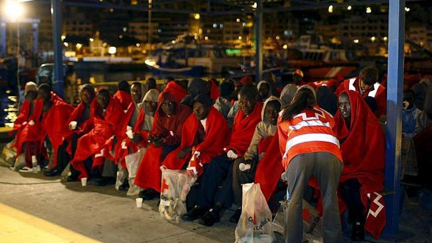 Varios de los 68 inmigrantes, de los que ocho podrían ser menores de edad, que viajaban a bordo de un cayuco que fue interceptado anoche a 110 millas de Gran Canaria, son atendidos por personal sanitario de Cruz Roja,