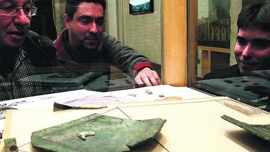 Los tres arqueólogos del CSIC observan las piezas de bronce halladas en el yacimiento de El Picón.