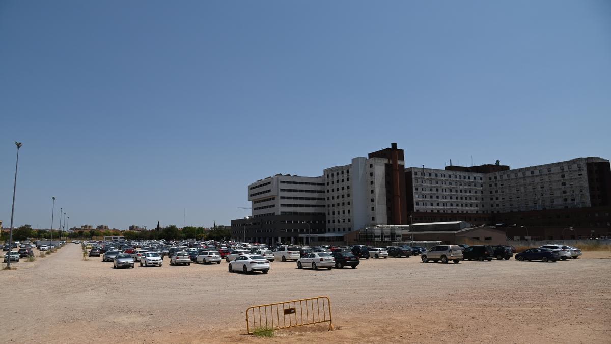 Vehículos aparcados en la zona de tierra junto al hospital Universitario de Badajoz.