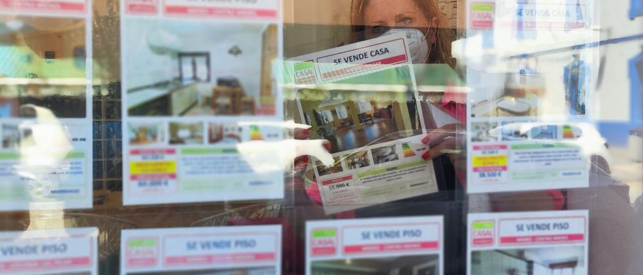 Una treballadora d’una immobiliària col·loca cartells a l’aparador. | A. VELASCO
