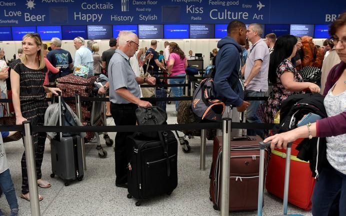 People queue with their luggage for the British ...