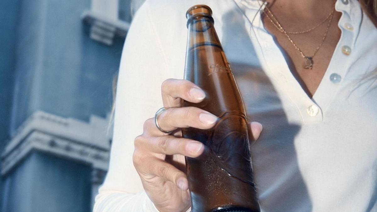 Una mujer sujetando una botella de cerveza Rivera Reposada.