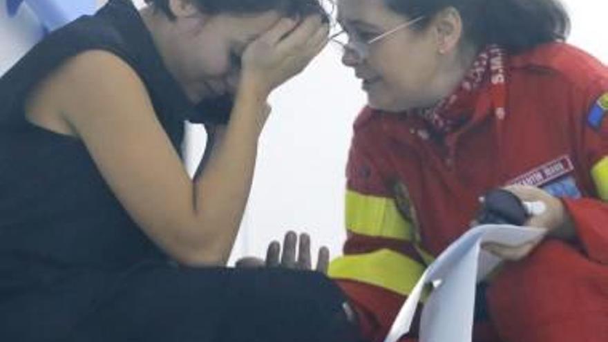 Uno de los heridos es trasladado a un centro hospitalario mientras personal sanitario consuela a una de las víctimas del incendio.