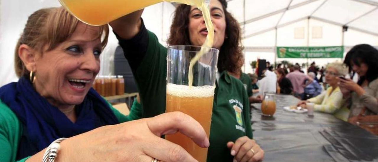 Una mujer sirve un vaso de sidra en una pasada edición de la fiesta. // José Lores