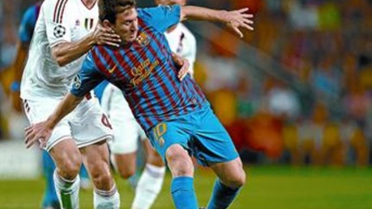 Van Bommel sujeta a Messi, durante el partido de anoche en el Camp Nou entre el Milan y el Barça.