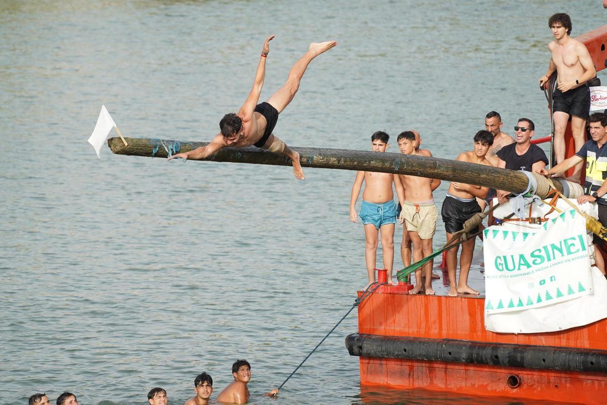 La 'cucaña', el juego centenario que regresa cada verano al río Guadalquivir por la Velá de Santa Ana en imágenes