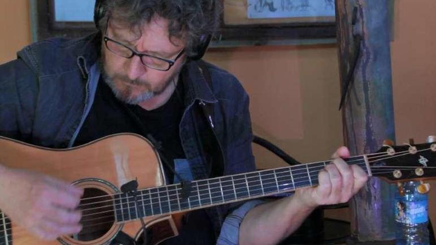 Fernando Maés, toca la guitarra en una grabación.