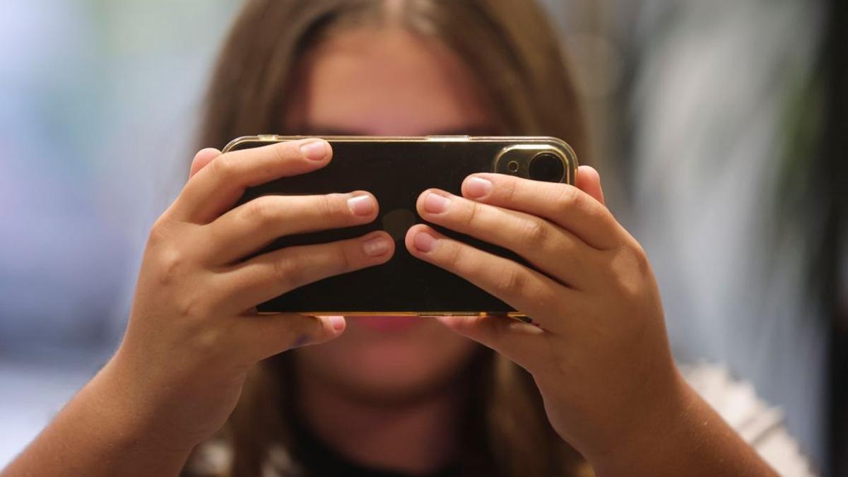 Una adolescente visualiza un contenido en su teléfono móvil.