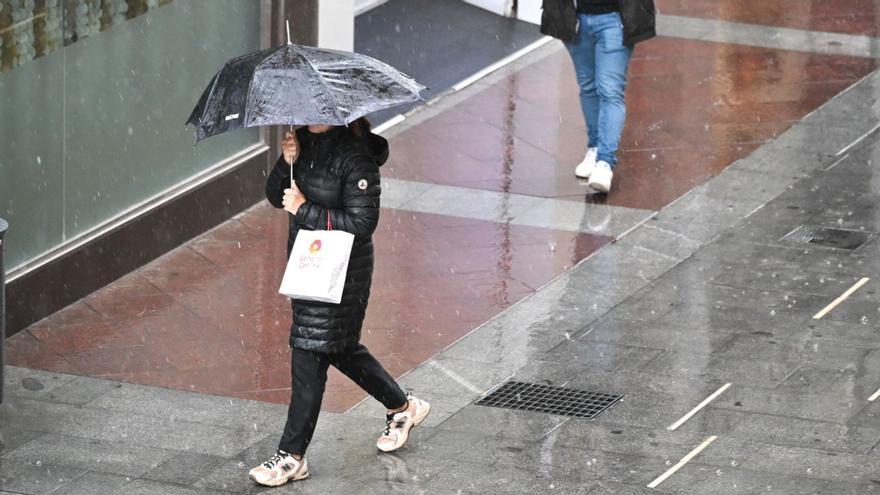 Una mujer protegiéndose de la lluvia con un paraguas en el centro de Elche.