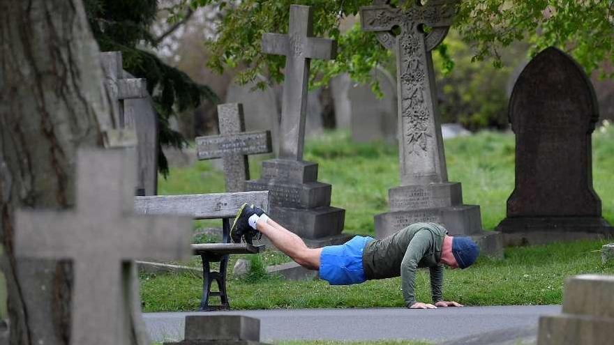 Un hombre hace ejercicio en un cementerio, ayer en Londres. // Reuters